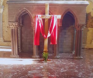 Photo d'une croix drapée de pourpre et illuminée