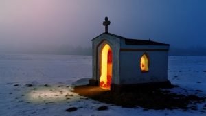 photo d'une chapelle isolée, allumée de l'intérieur.