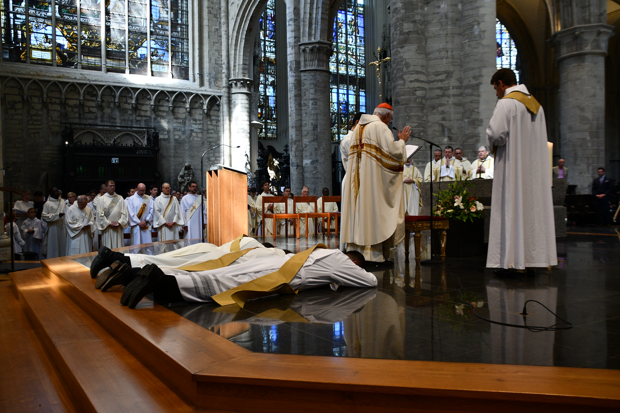 Photo des ordinations presbytérales 2023 en la cathédrale de Bruxelles. On voit les trois diacres allongés par terre dans le choeur de l'église.