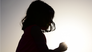photo d'un enfant en contre-jour sur un fond gris et lumineux. Cela représente les enfants victimes d'abus sexuels dans l'Eglise